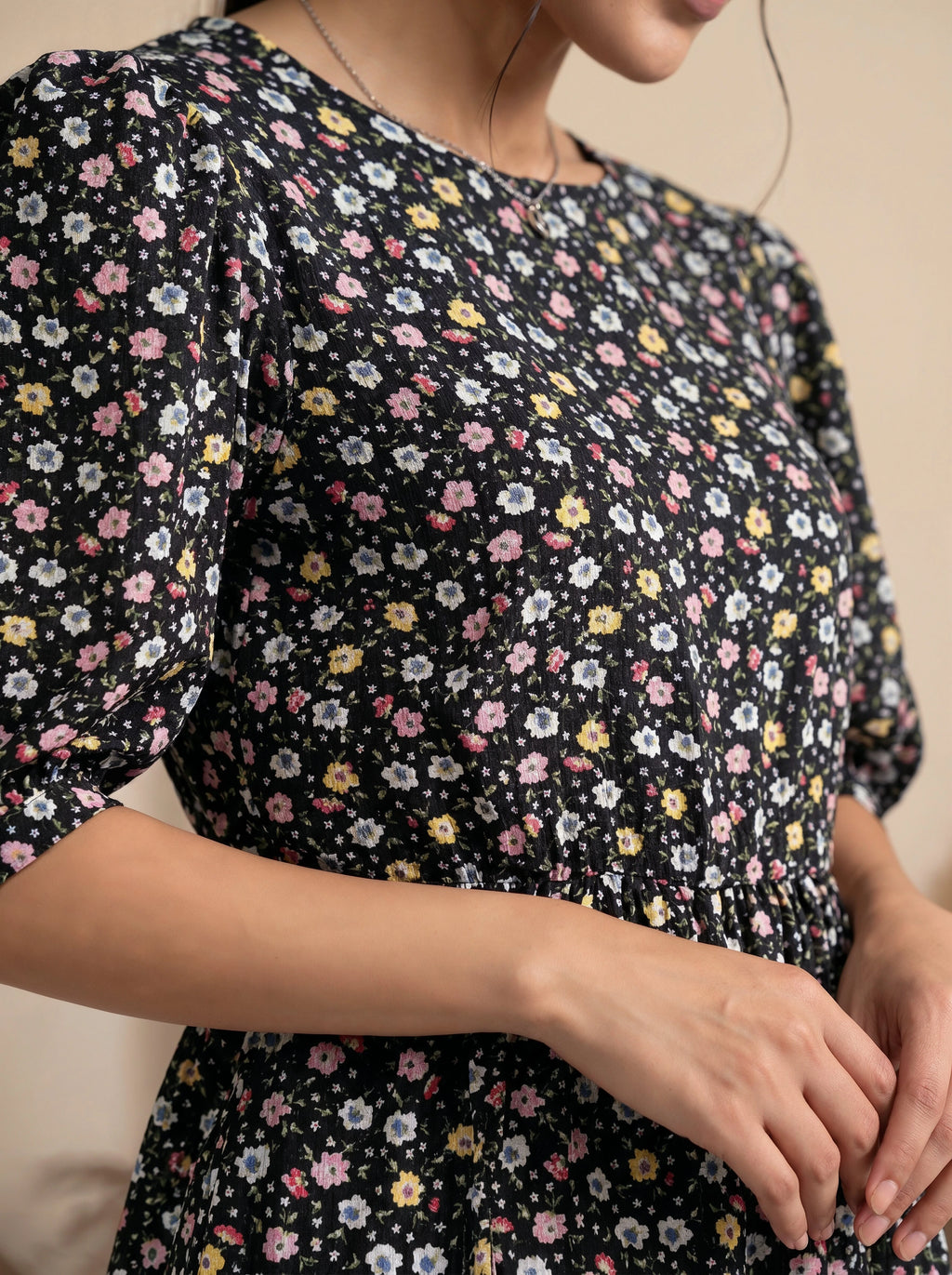 Woman wearing a black floral dress with a neutral background