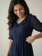 Woman wearing a navy blue dress against a plain background