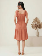 Woman wearing a rust-colored dress with a neutral background