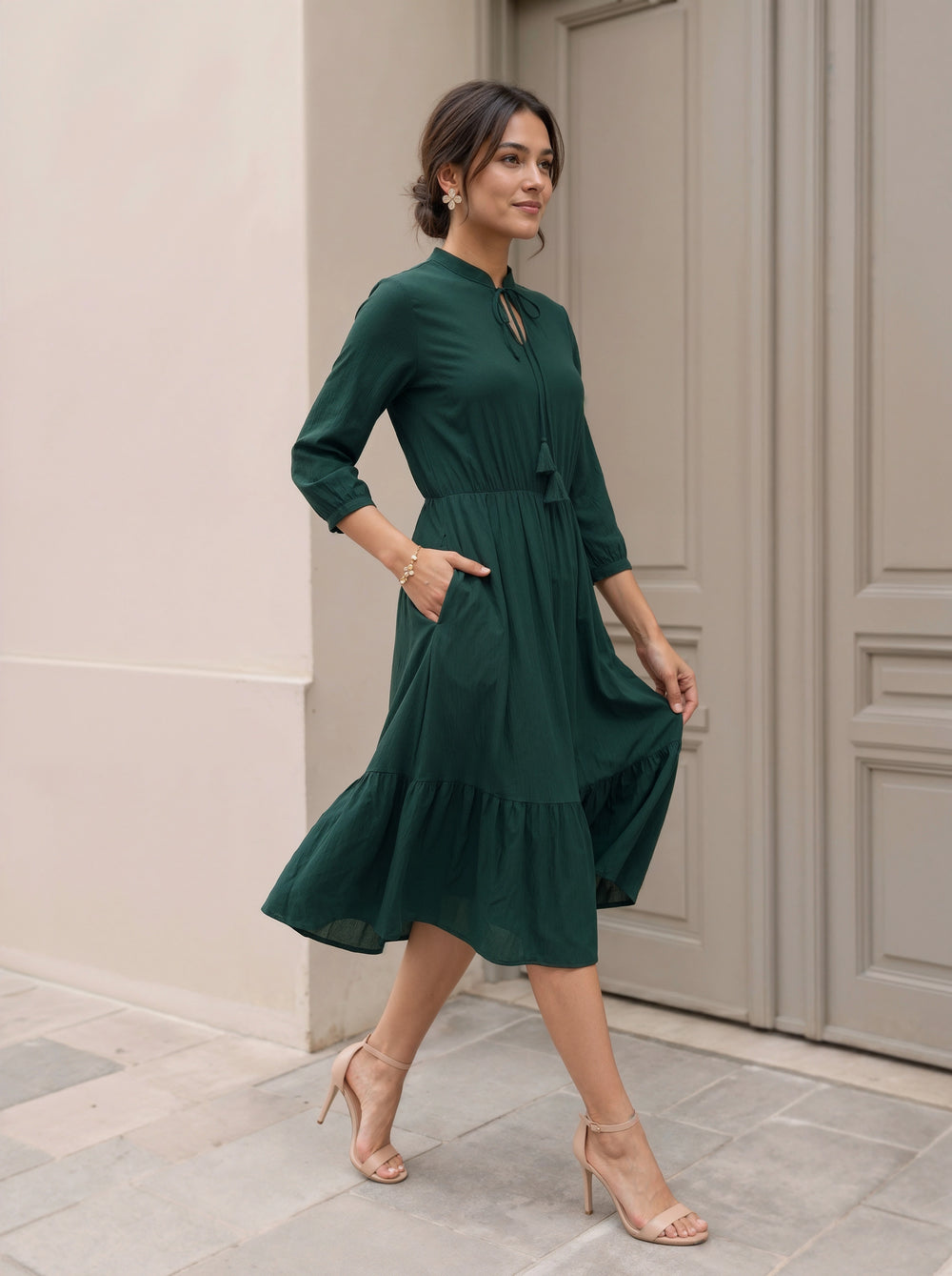 Woman in a green dress standing in front of a door.