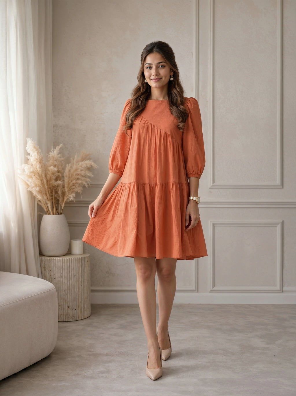 Woman wearing an orange dress standing in a room with neutral decor.