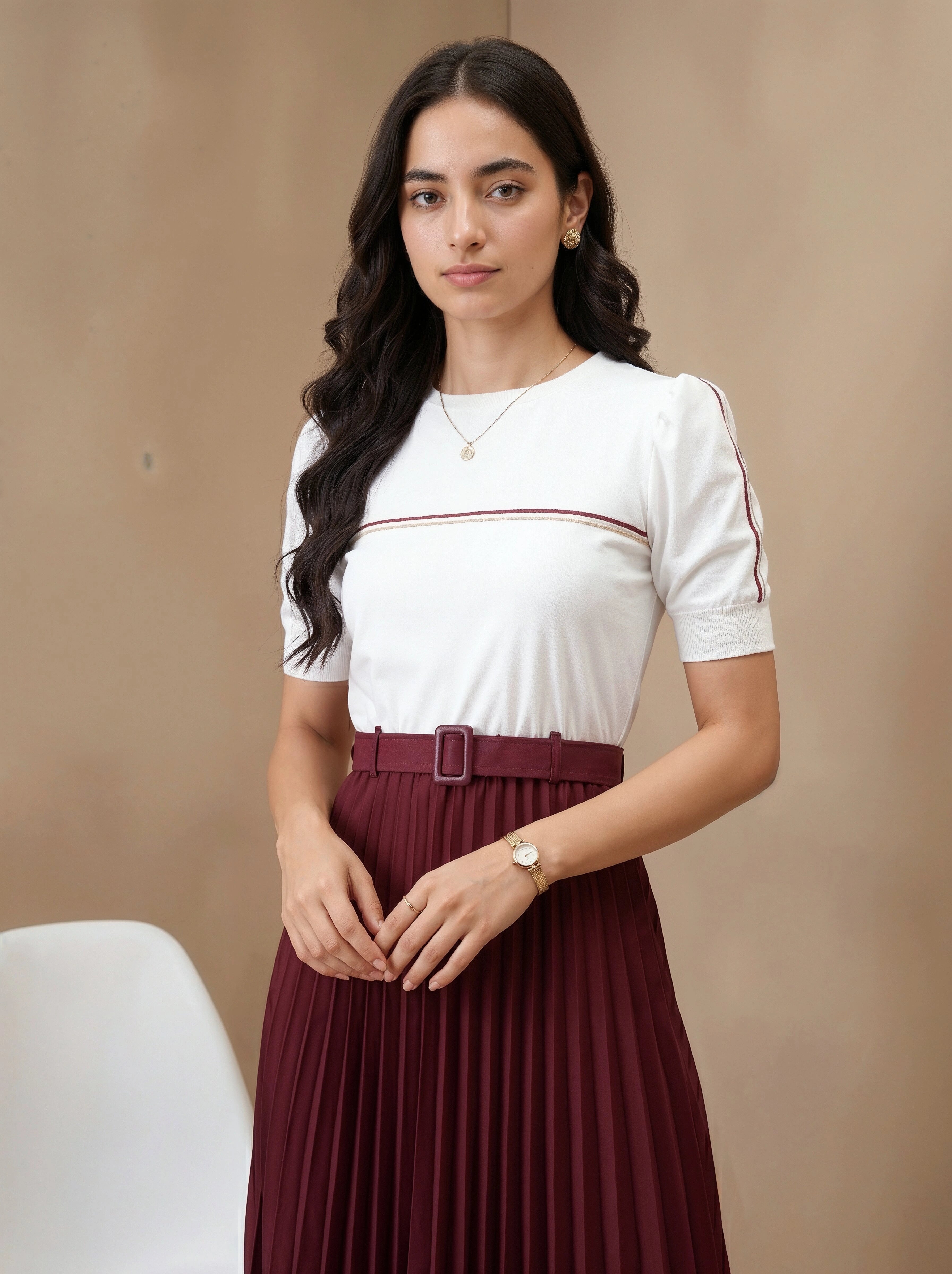 Woman wearing a white top with red trim and a maroon pleated skirt against a beige background