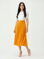 Woman wearing a white top and orange pleated skirt on a white background