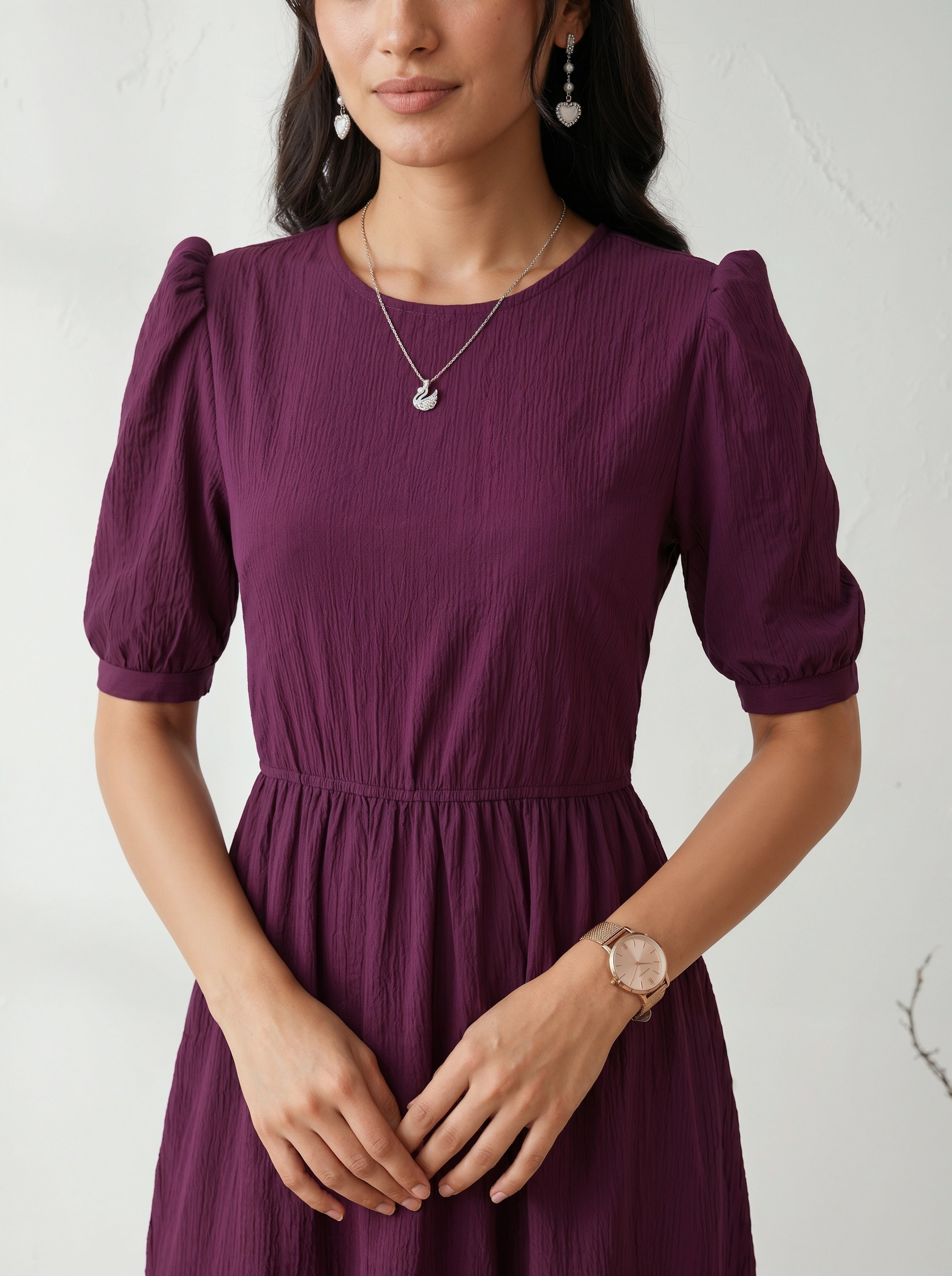 Woman wearing a purple dress with puff sleeves against a white background