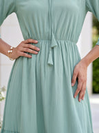 Person wearing a light green dress with a blurred background