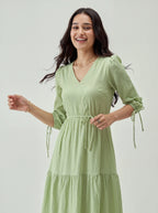 Woman wearing a light green dress with puff sleeves on a plain background
