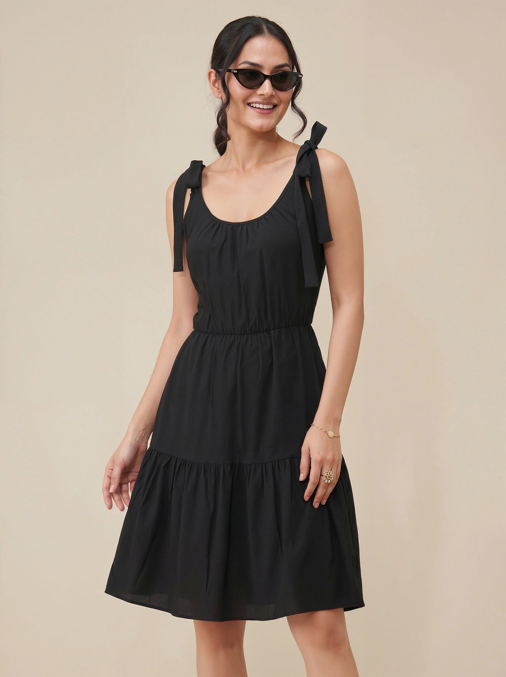 Woman wearing a black dress with bow straps on a beige background