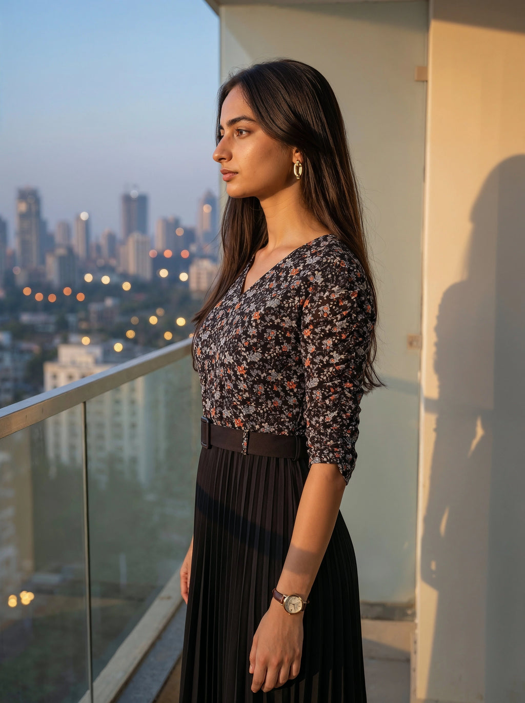 Woman standing on a balcony with a cityscape view at dusk