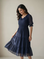 Woman wearing a navy blue dress against a beige background
