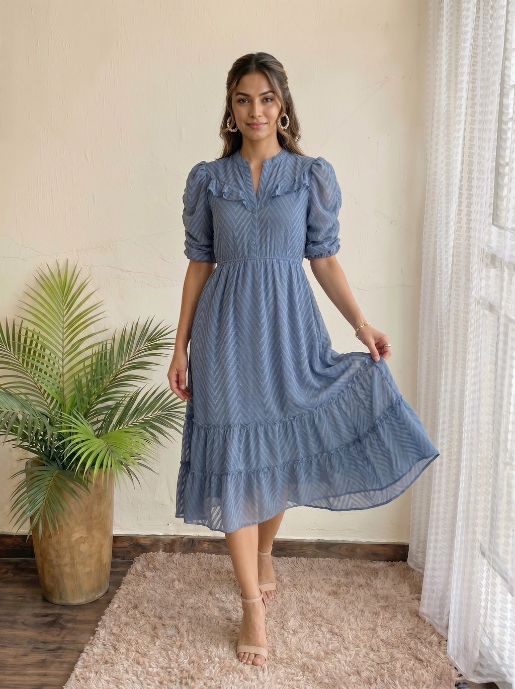 Woman smiling in a tiered dusty blue dress in a bright room