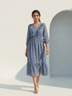 Woman wearing a blue dress with lace details against a white background