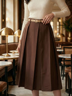Person wearing a beige top and brown skirt in a café setting