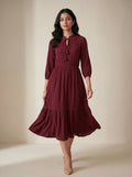Woman wearing a burgundy dress against a beige background