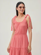 Woman wearing a pink dress with bow straps on a plain background