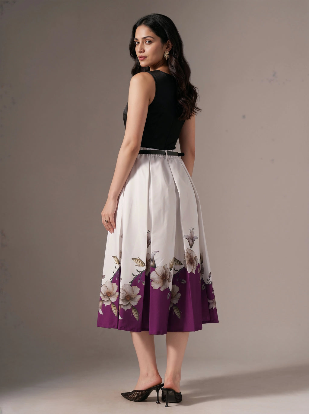 Woman wearing a black top and floral skirt with purple accents on a plain background