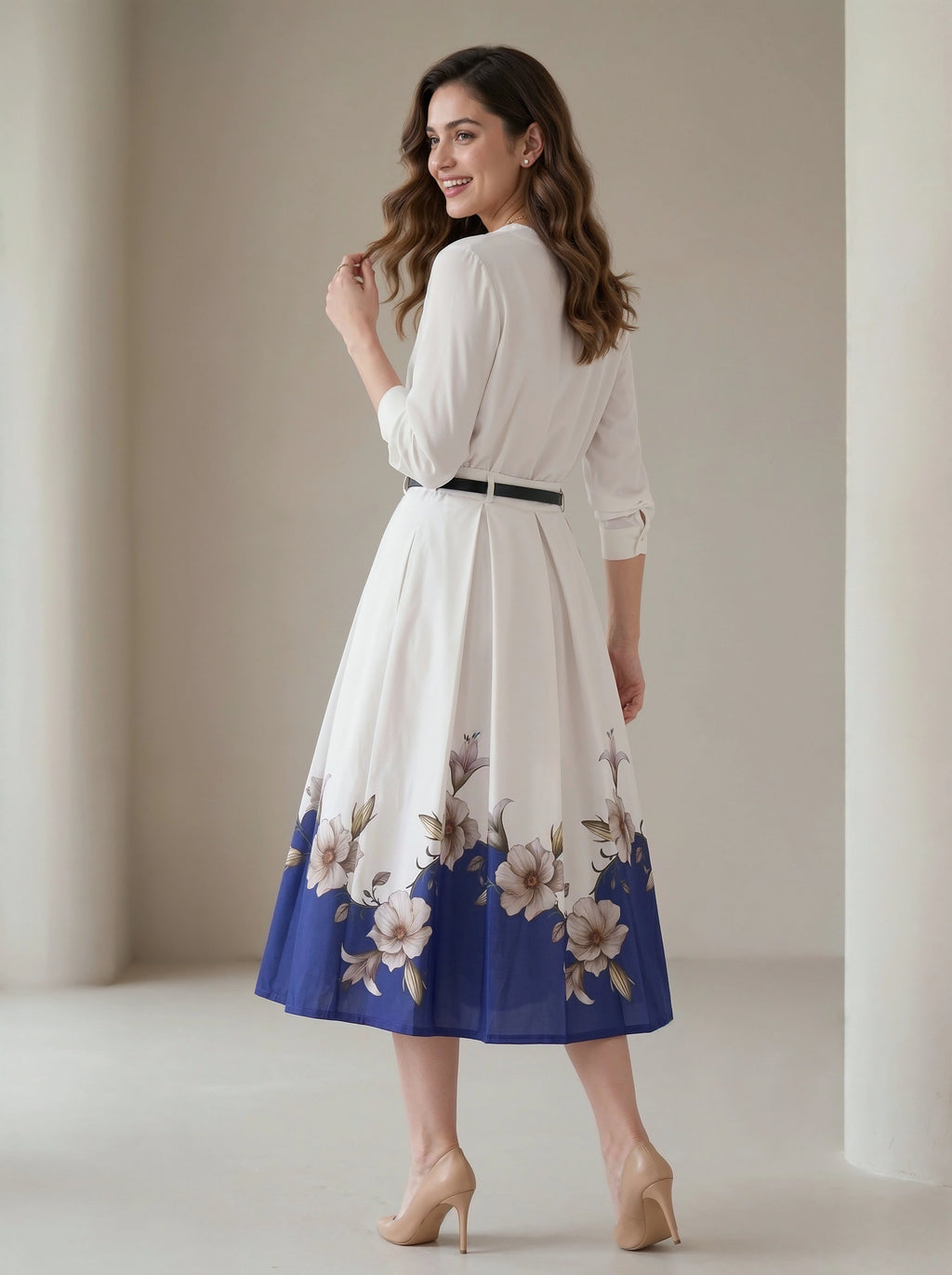Woman wearing a white dress with floral blue hem in a neutral setting