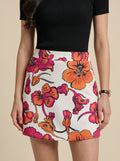 Person wearing a floral skirt with orange and pink flowers on a beige background