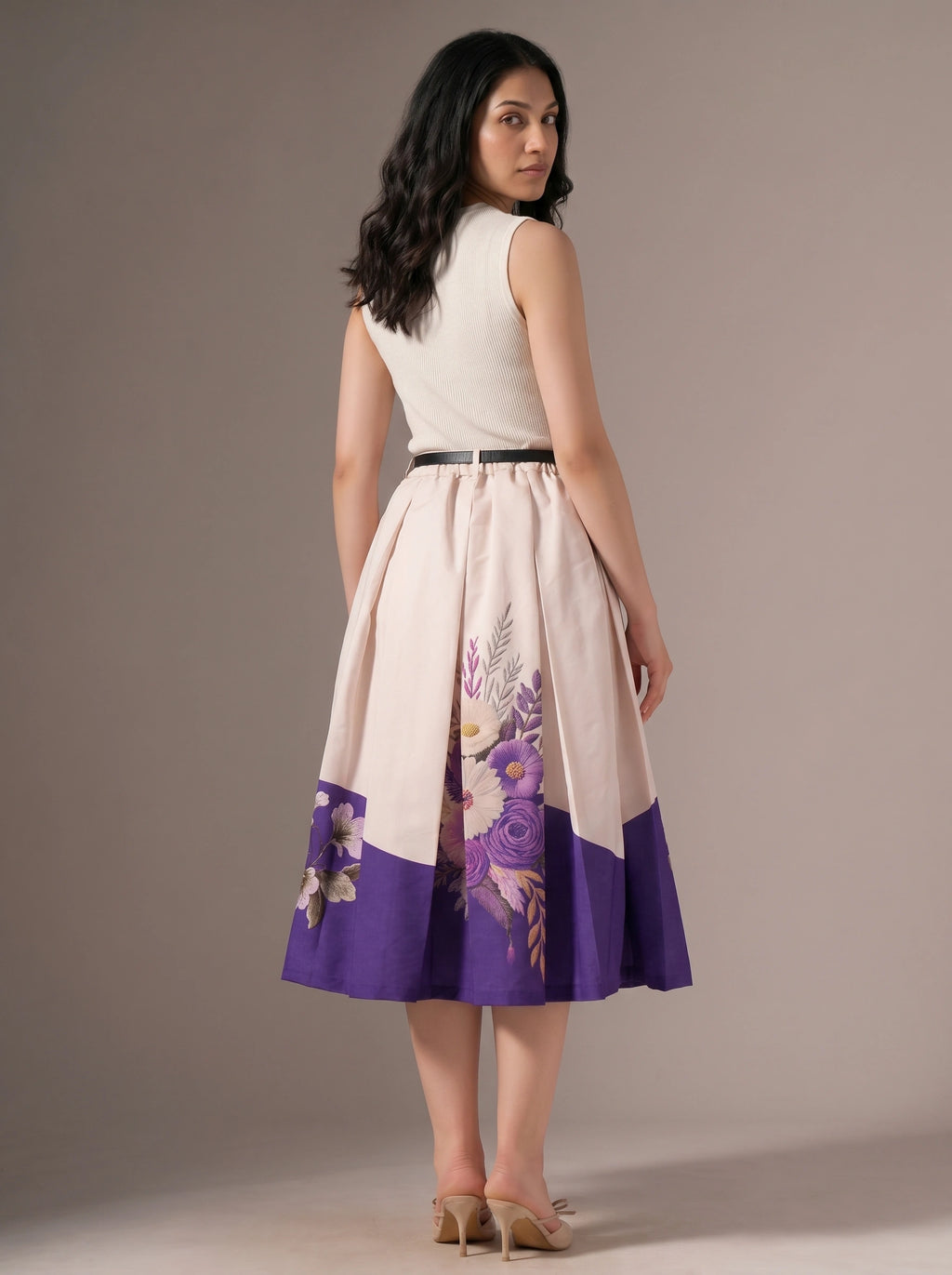 Woman wearing a dress with floral design and purple accents on a plain background