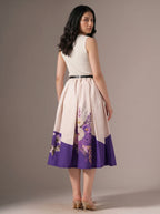 Woman wearing a dress with floral design and purple accents on a plain background