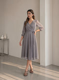 Woman wearing a gray patterned dress in an indoor setting