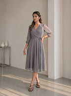 Woman wearing a gray patterned dress in an indoor setting