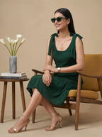 Woman in a green dress sitting on a chair with a beige background