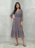 Woman wearing a long, patterned dress against a plain background