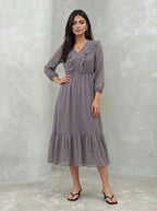 Woman wearing a long, patterned dress against a plain background