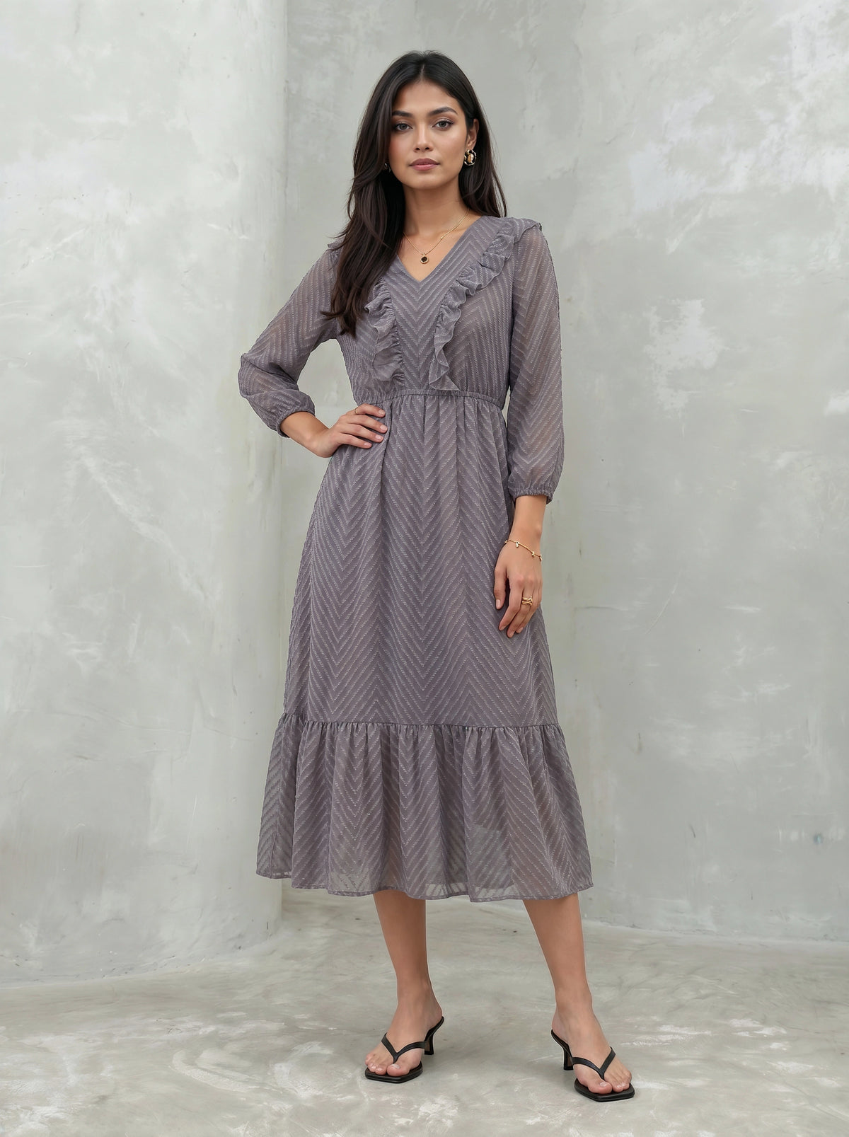 Woman wearing a long, patterned dress against a plain background