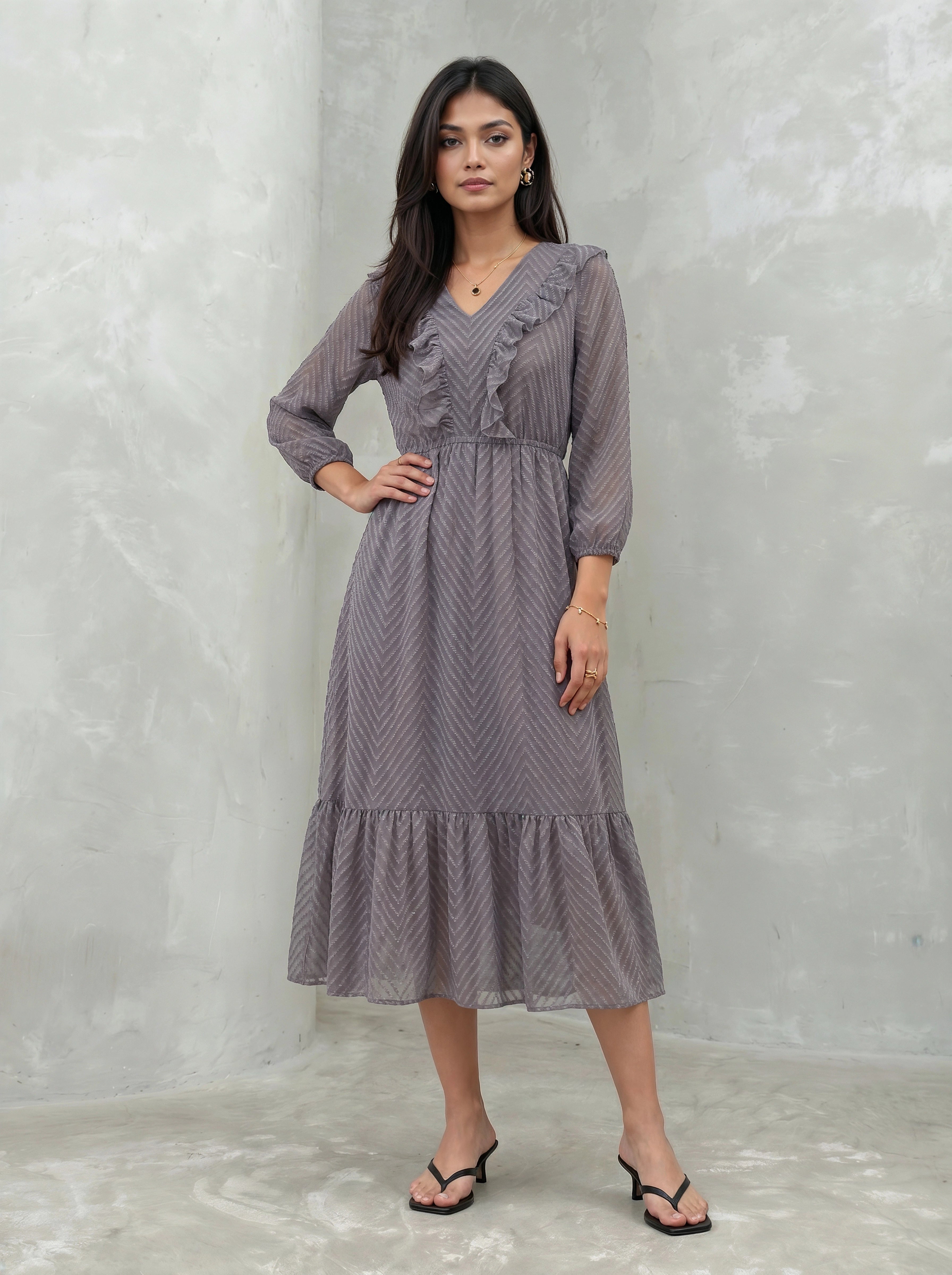 Woman wearing a long, patterned dress against a plain background