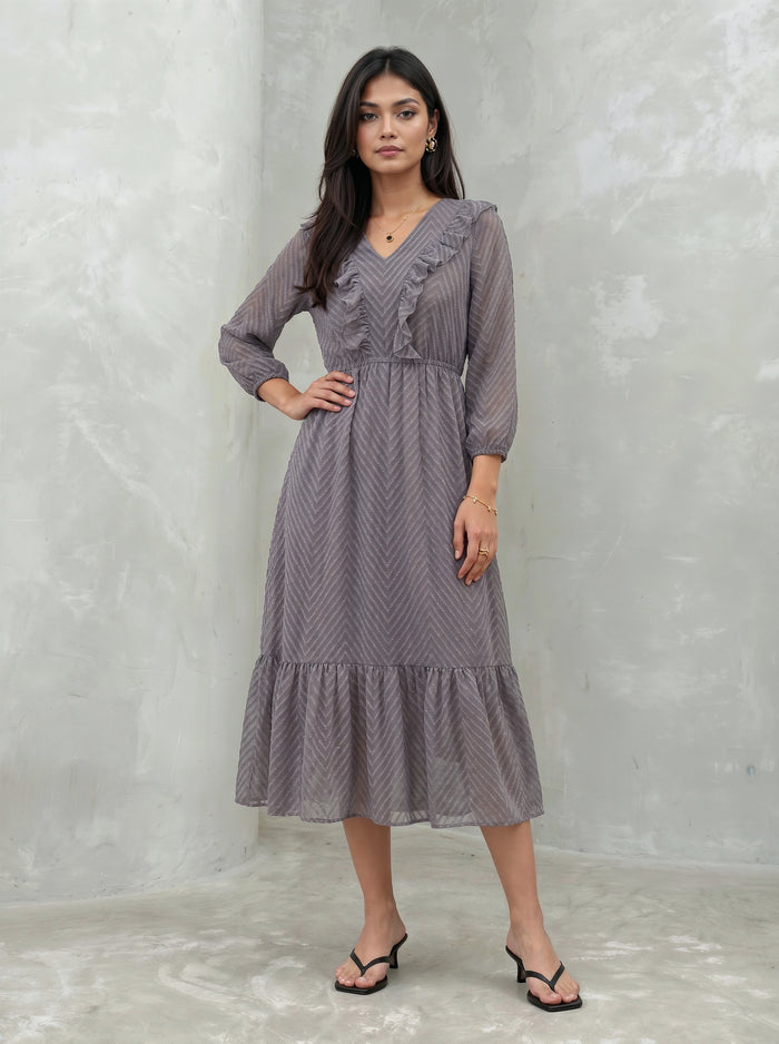 Woman wearing a long, patterned dress against a plain background