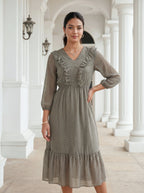 Woman wearing a gray patterned dress in an elegant interior setting