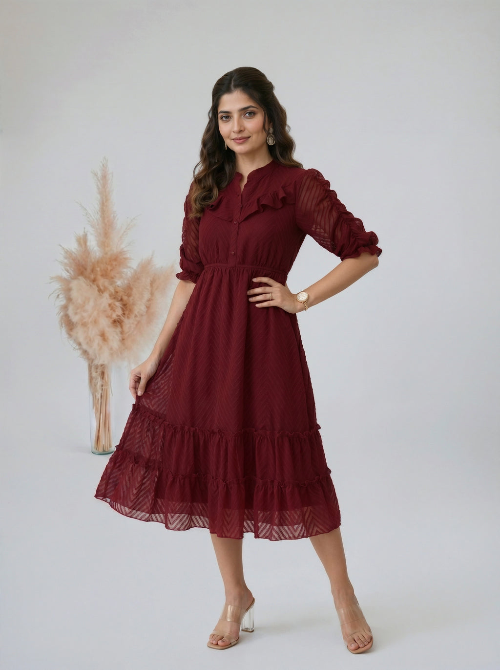 Woman posing in a tiered dark red dress in a minimalist setting