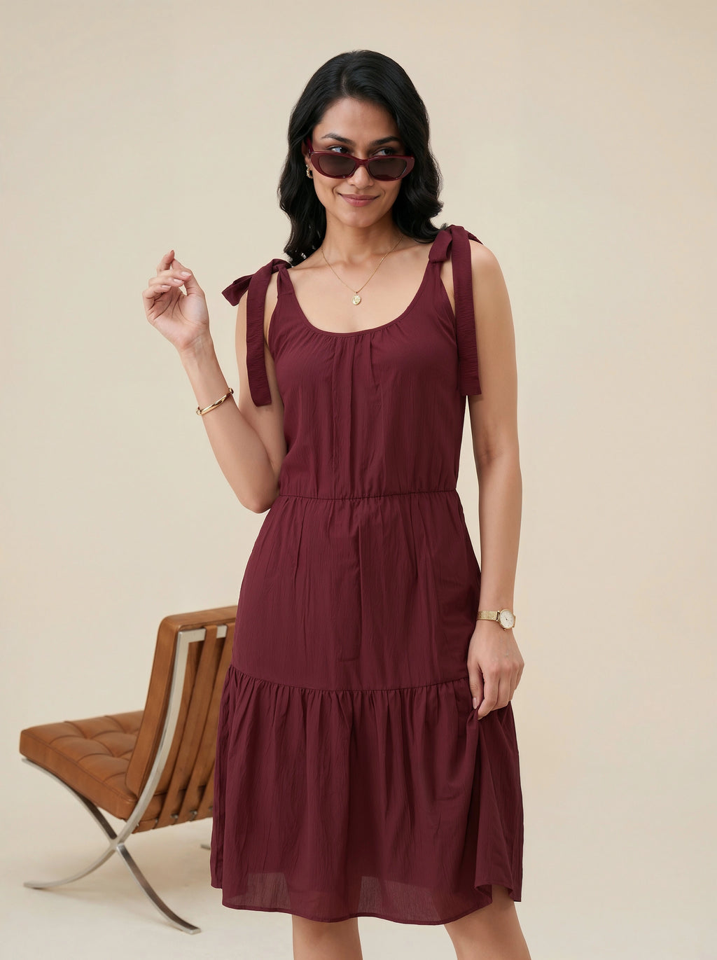 Woman wearing a burgundy dress with bow straps against a beige background