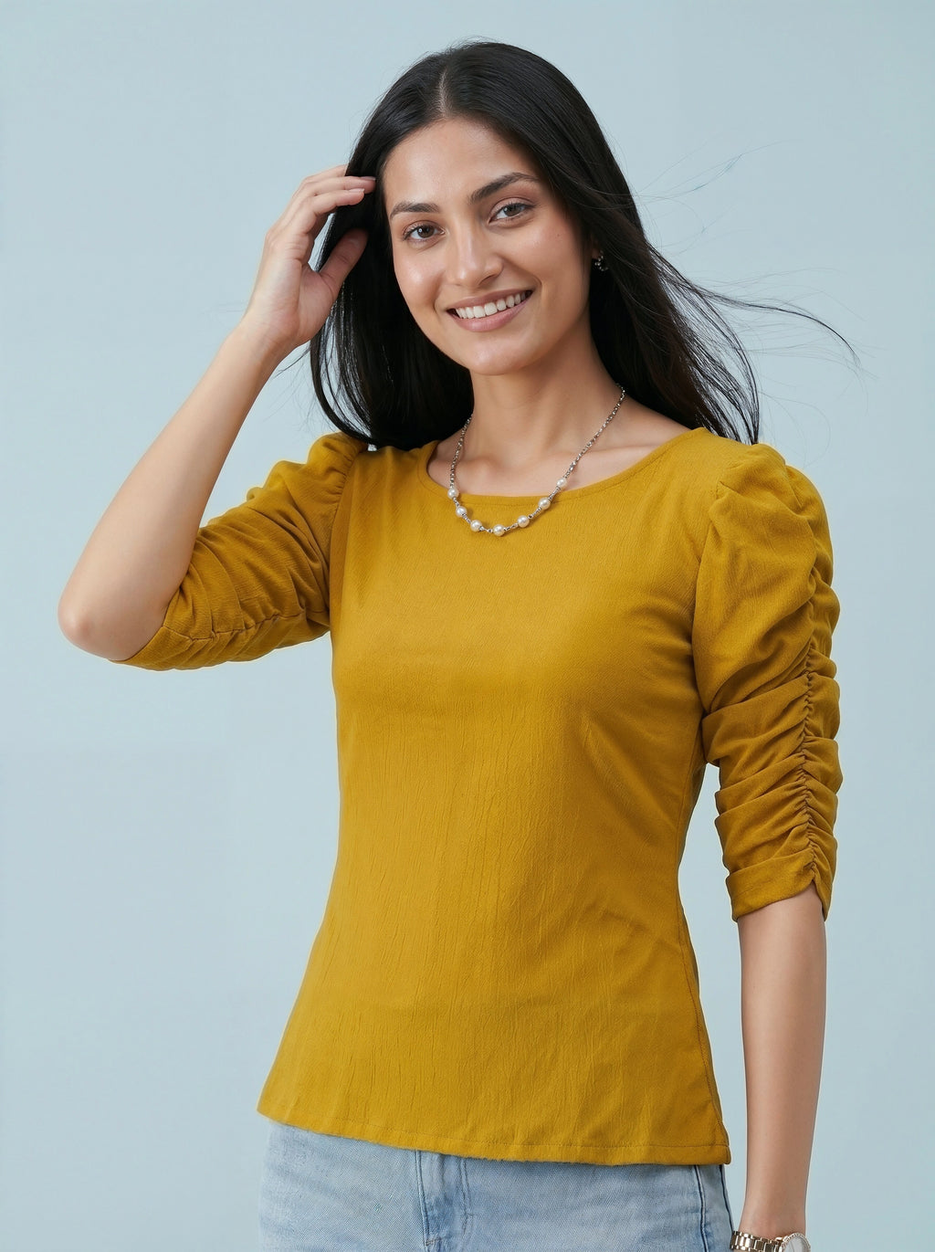 Woman wearing a yellow top with ruched sleeves against a light blue background