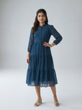 Woman wearing a blue dress with long sleeves on a white background