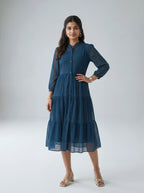 Woman wearing a blue dress with long sleeves on a white background