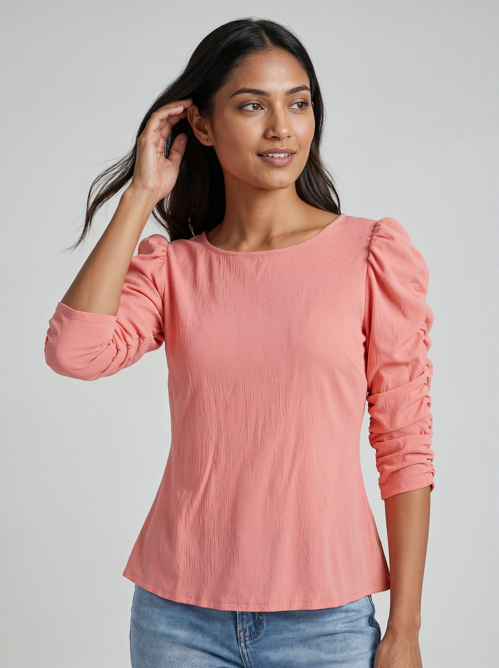 Woman wearing a pink blouse with puffed sleeves against a plain background