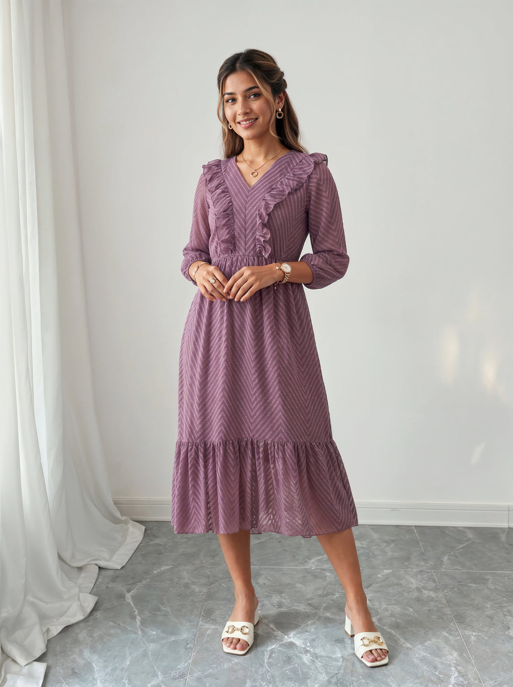 Woman wearing a purple dress standing against a white wall.