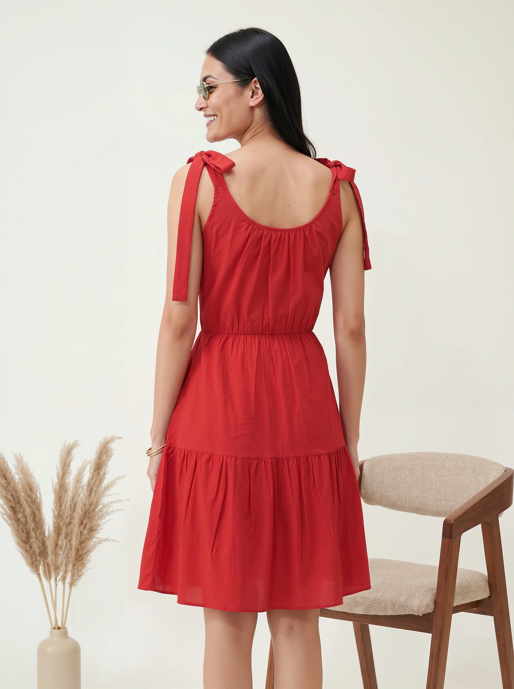 Woman wearing a red dress with bow straps against a white background