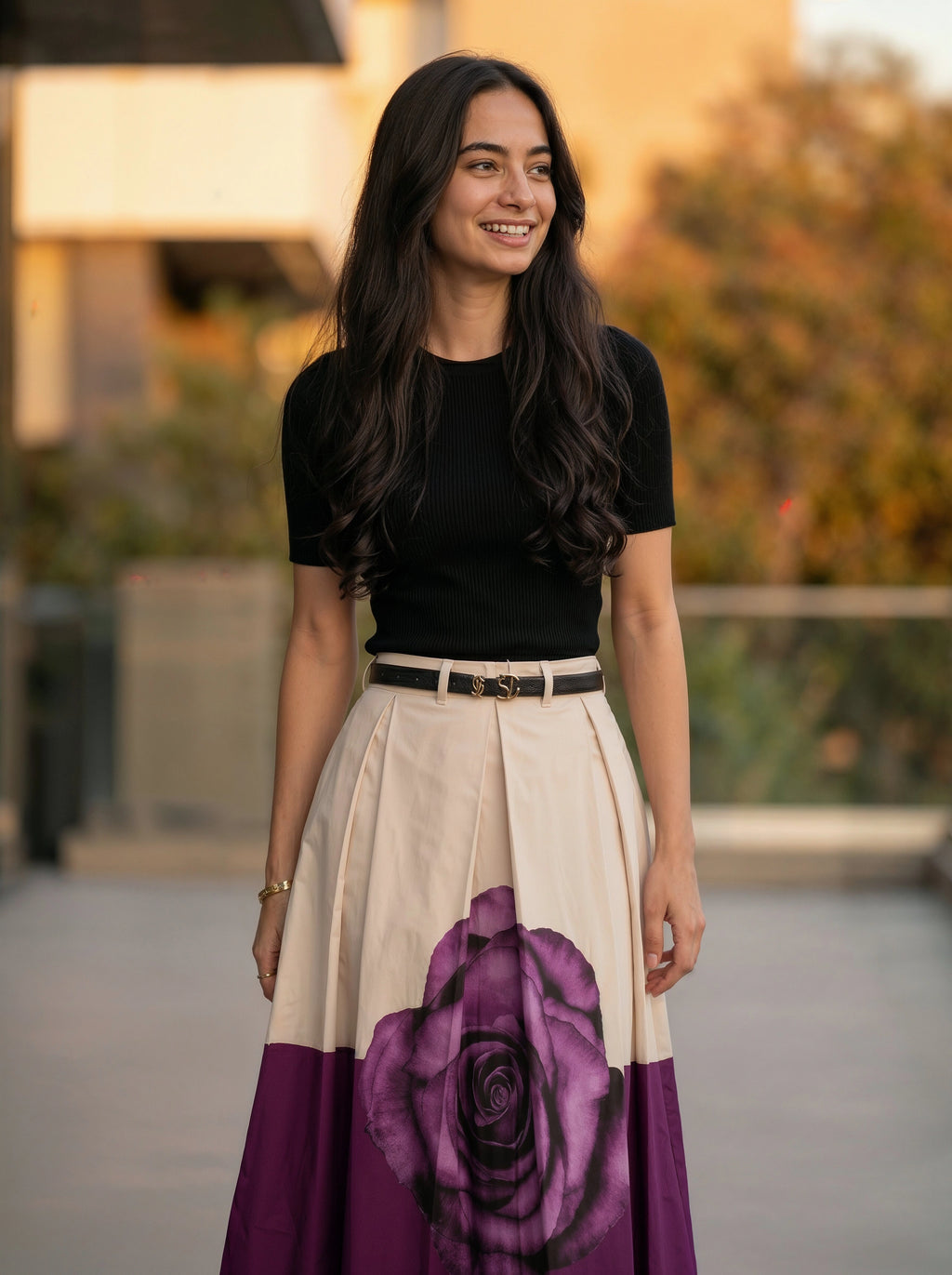 Woman wearing a black top and a long skirt with a purple rose design outdoors.