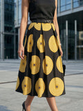 Person wearing a black top and a black and yellow patterned skirt in an urban setting.