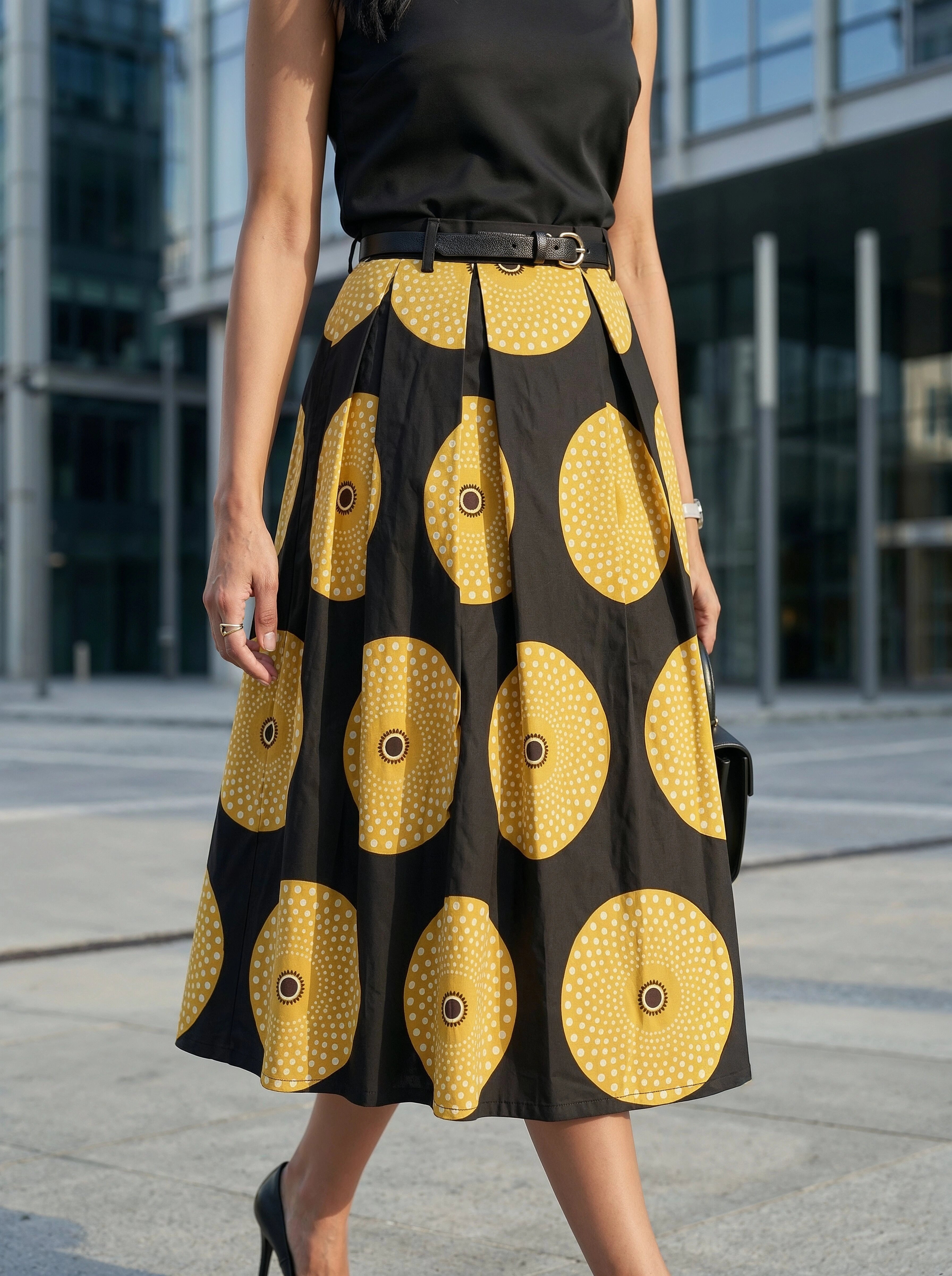 Person wearing a black top and a black and yellow patterned skirt in an urban setting.