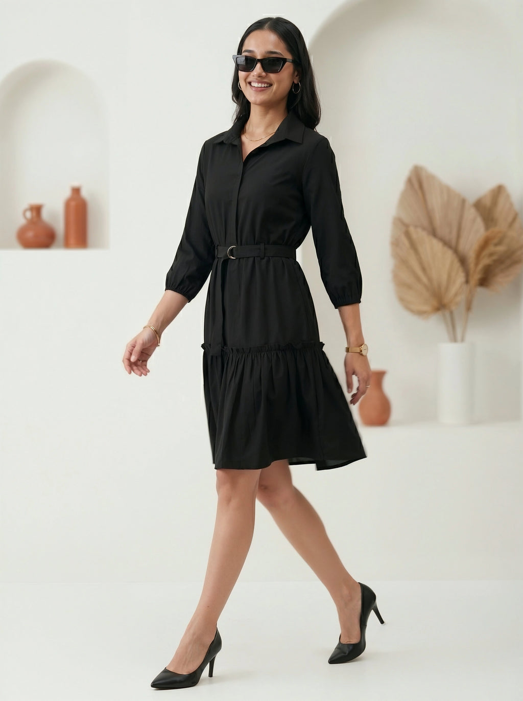 Woman wearing a black dress with sunglasses in a minimalistic setting