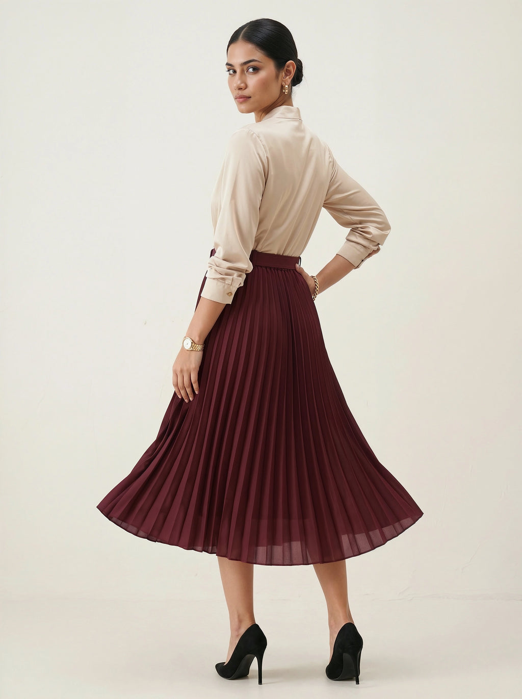 Woman wearing a beige blouse and burgundy pleated skirt on a white background