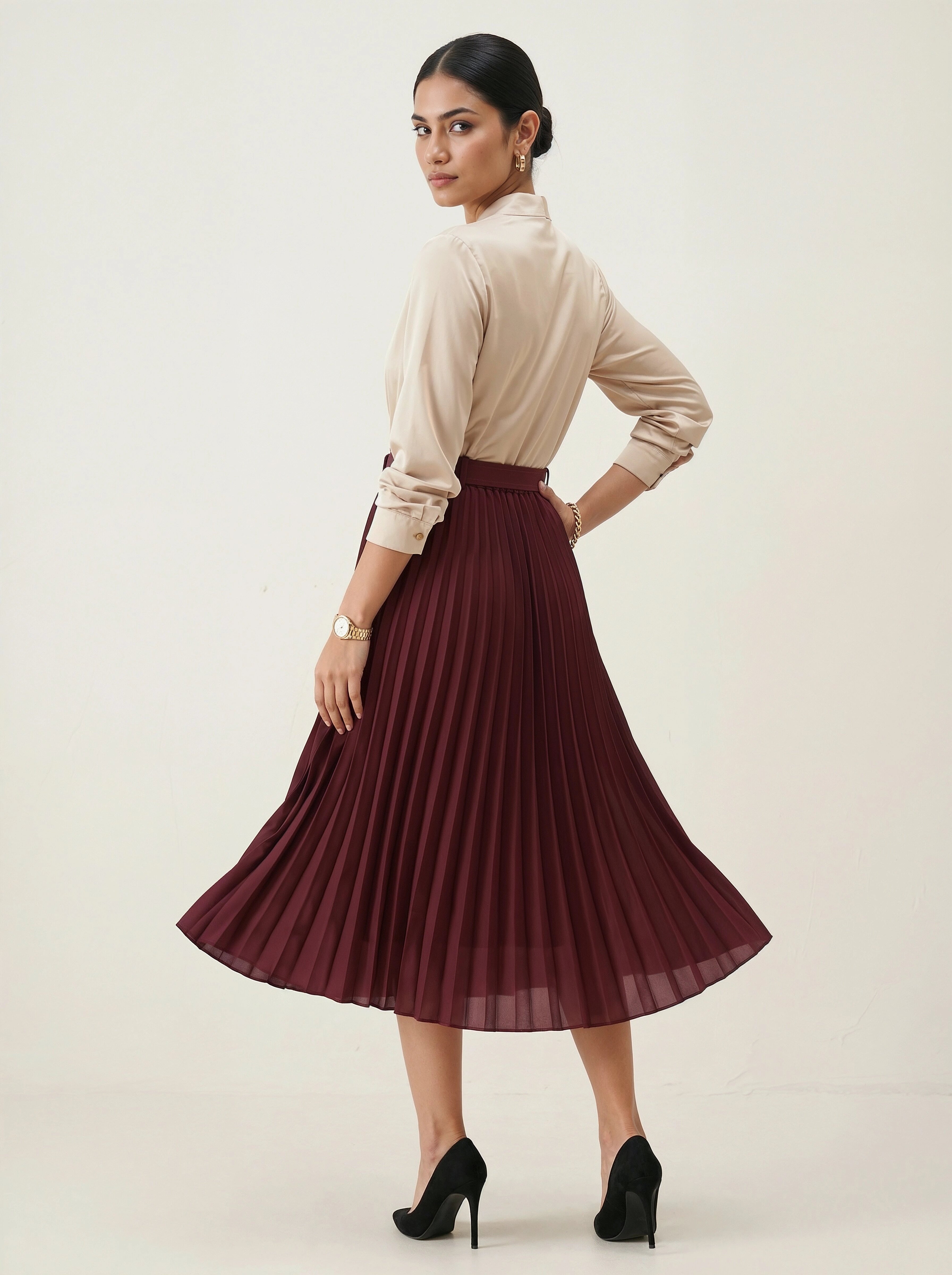 Woman wearing a beige blouse and burgundy pleated skirt on a white background