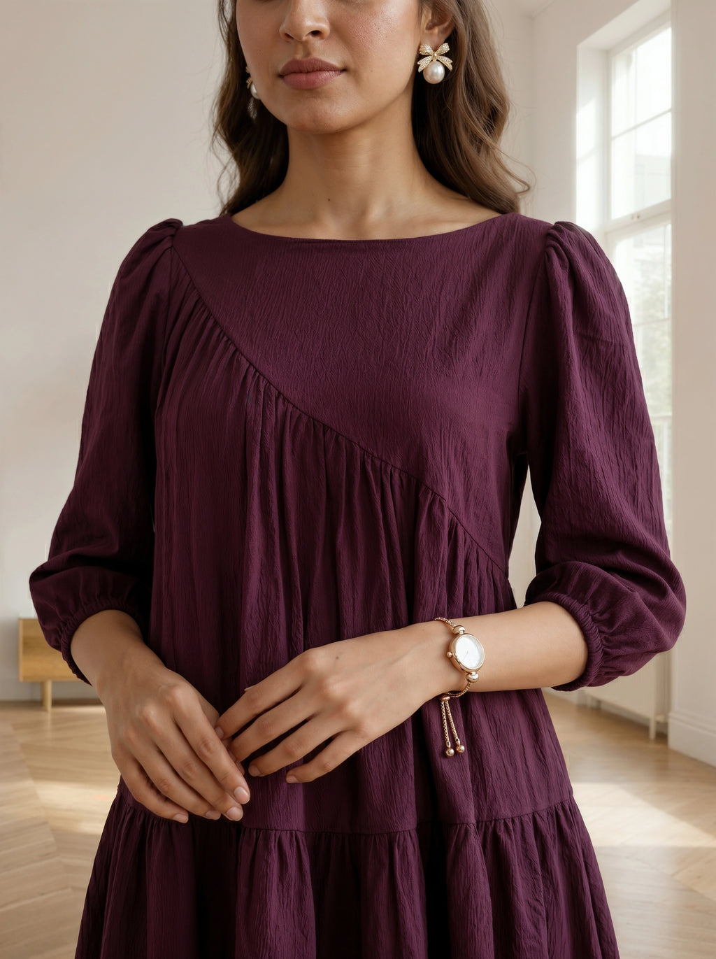 Woman wearing a burgundy dress with long sleeves in a bright room.