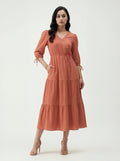 Woman wearing a rust-colored dress on a white background