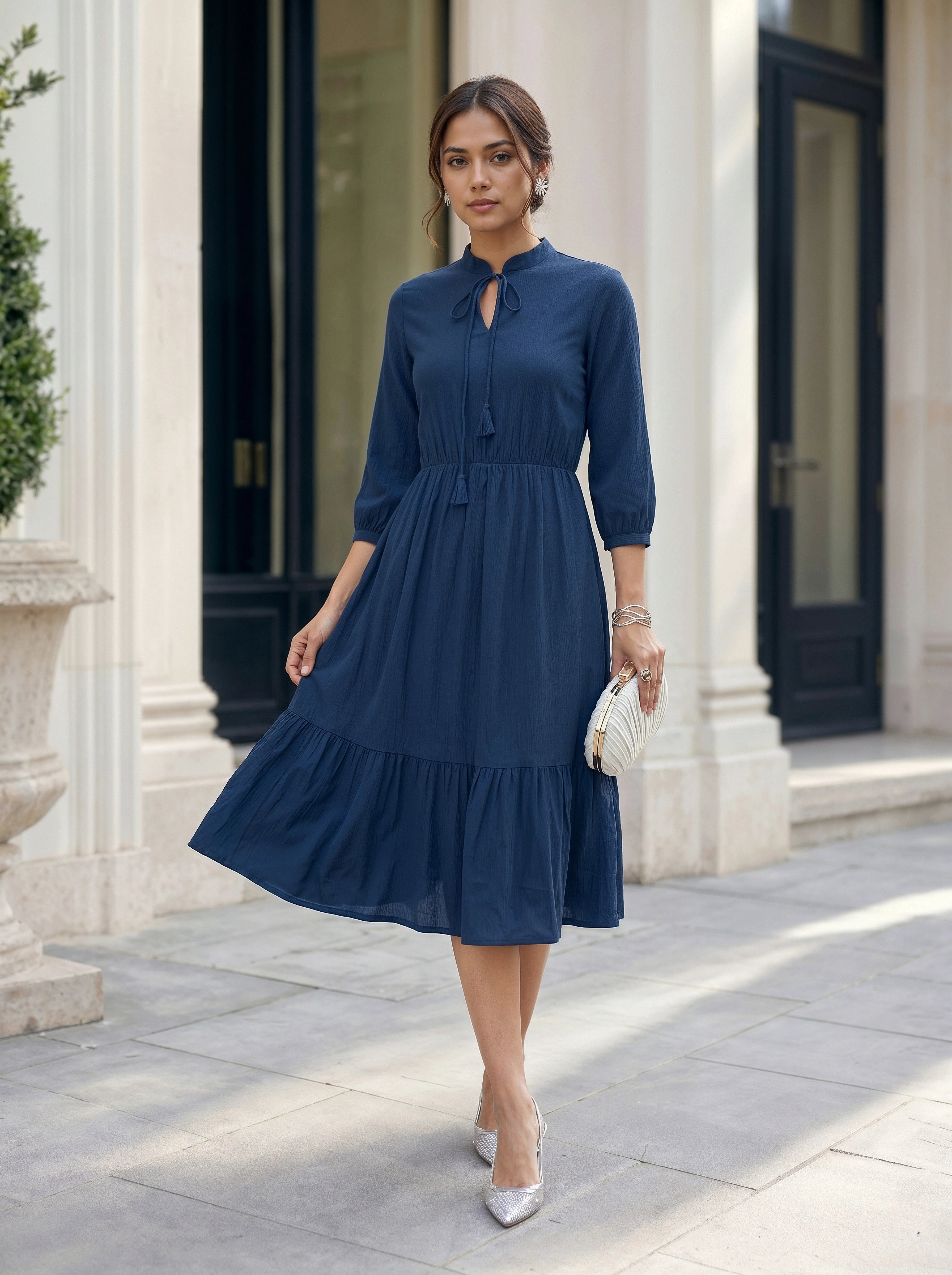 Woman wearing a blue dress standing in front of a building entrance.