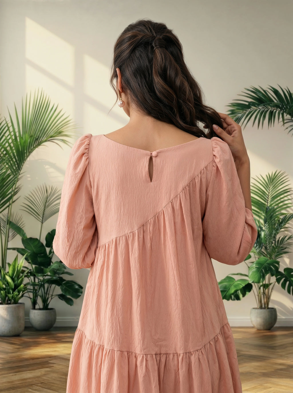 Woman in a pink dress standing in a room with plants